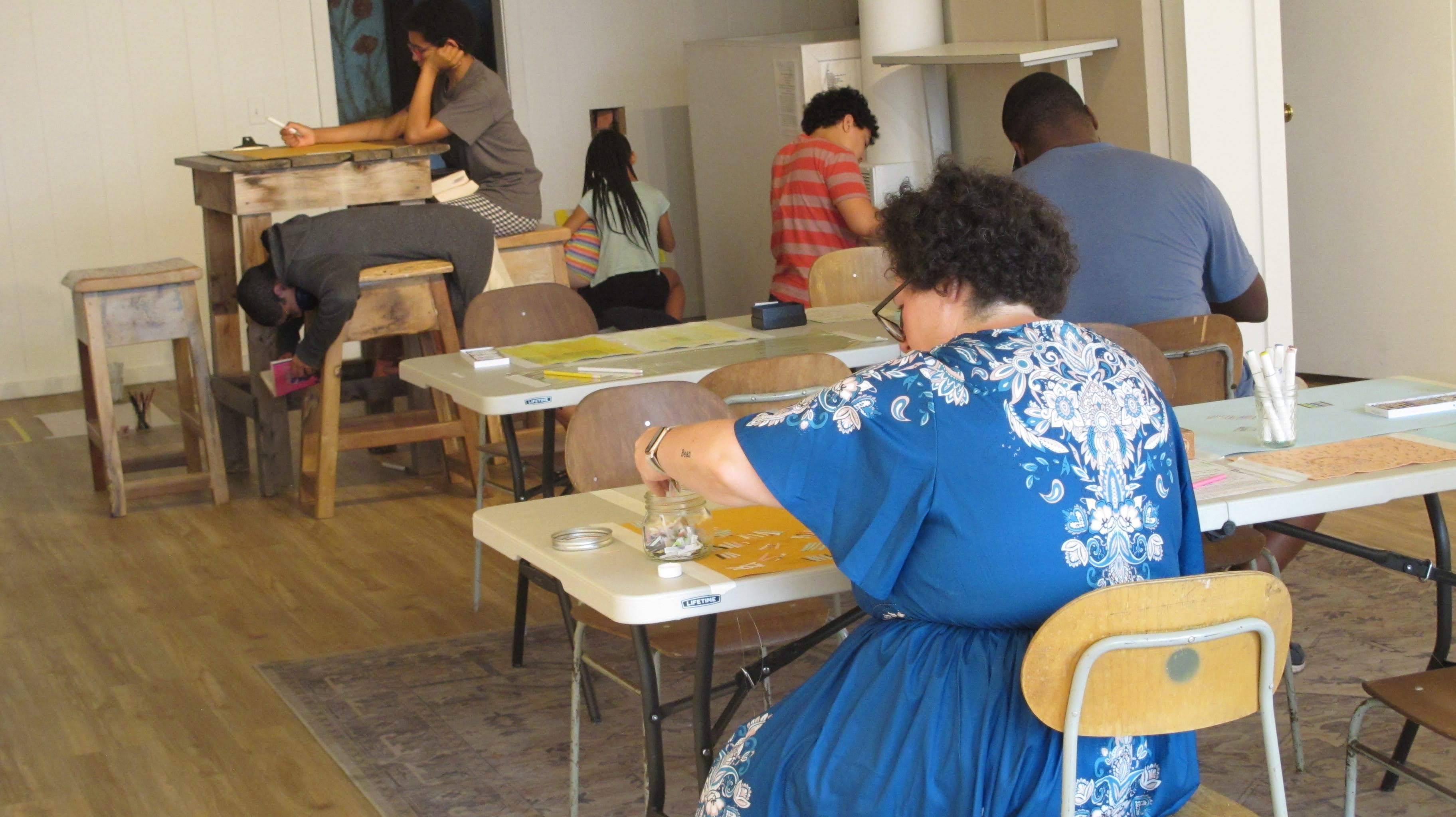 image of people sitting at tables draing on paper